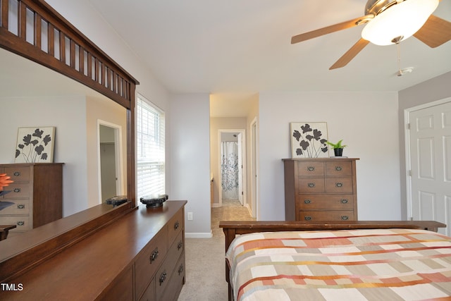 bedroom featuring ceiling fan, light colored carpet, and ensuite bath