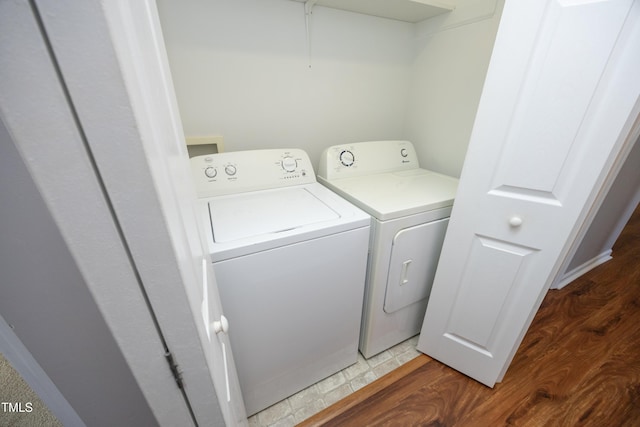 clothes washing area with independent washer and dryer and wood-type flooring