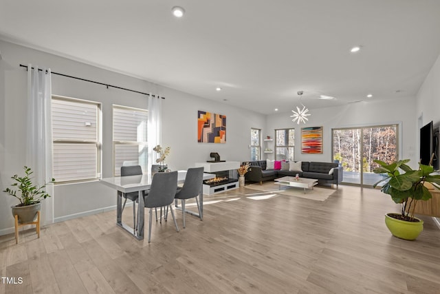 dining space featuring light wood finished floors, a glass covered fireplace, recessed lighting, and baseboards