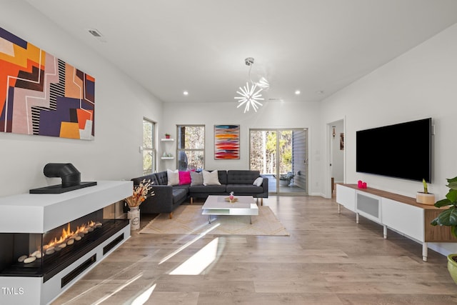 living room featuring a multi sided fireplace, recessed lighting, a healthy amount of sunlight, and wood finished floors