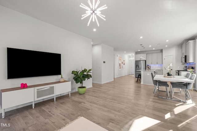 living room featuring baseboards, recessed lighting, light wood-type flooring, and a chandelier