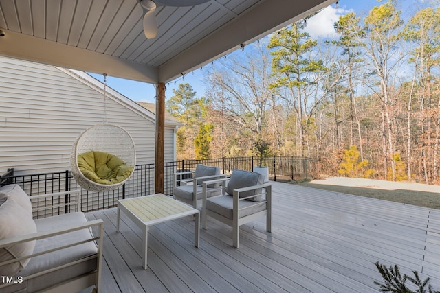 wooden deck featuring outdoor lounge area, a forest view, and a ceiling fan