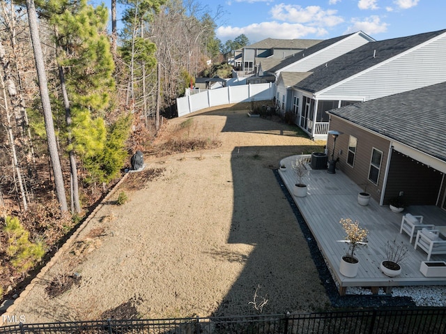 view of yard featuring central AC unit, a wooden deck, and fence