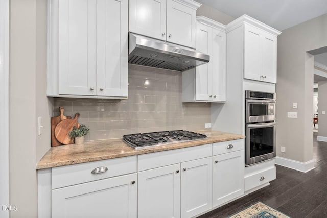 kitchen featuring decorative backsplash, white cabinetry, dark wood-type flooring, and appliances with stainless steel finishes