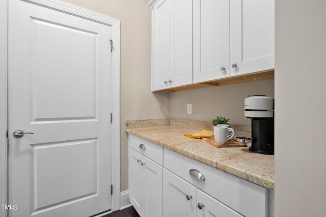 interior space with light stone countertops and white cabinets