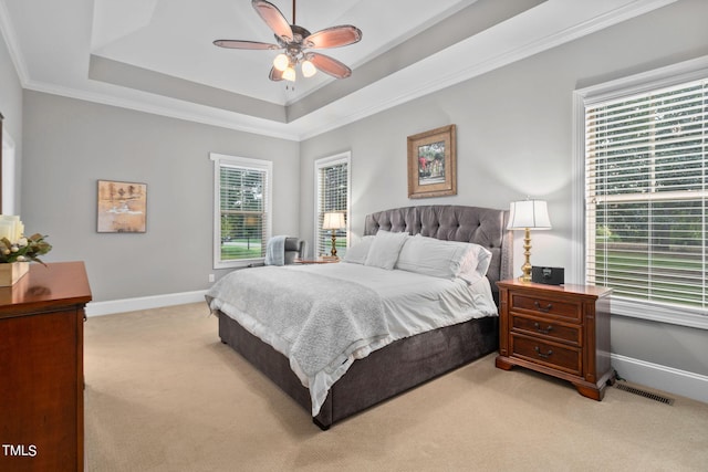 carpeted bedroom featuring a tray ceiling, ceiling fan, and crown molding