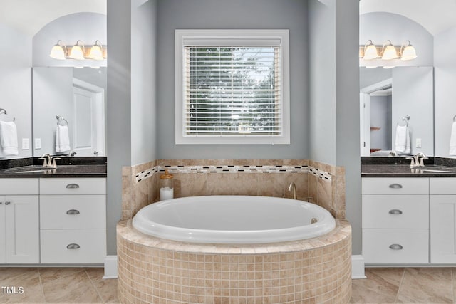 bathroom with tiled bath, tile patterned flooring, and vanity