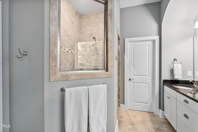 bathroom with a tile shower and vanity