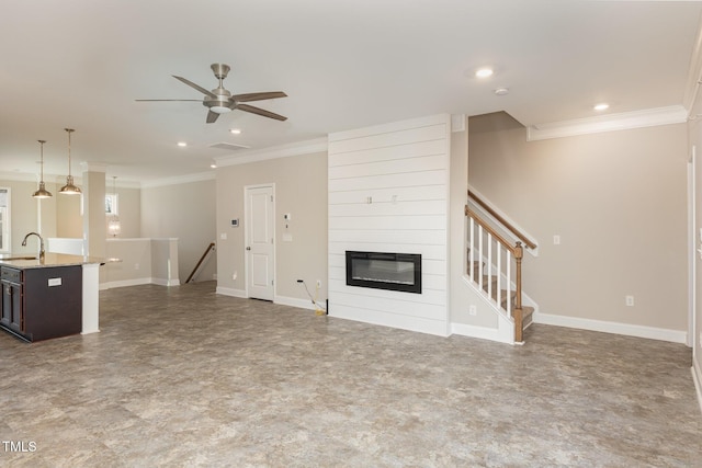 unfurnished living room featuring ceiling fan, ornamental molding, sink, and a fireplace