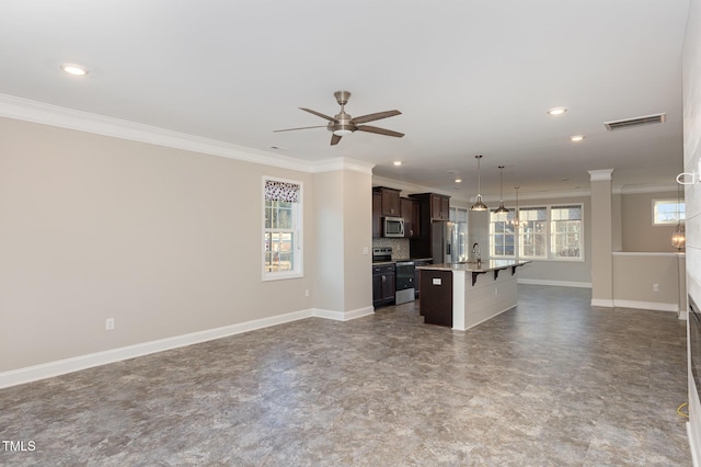 kitchen featuring pendant lighting, an island with sink, crown molding, appliances with stainless steel finishes, and dark brown cabinets