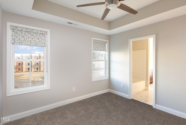 carpeted spare room with ceiling fan and a tray ceiling