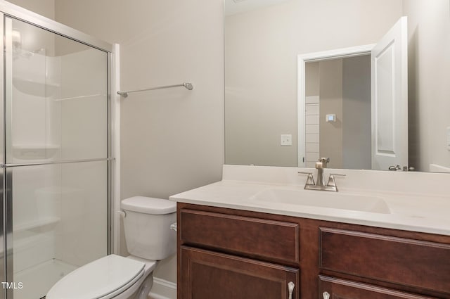 bathroom featuring a shower with shower door, vanity, and toilet