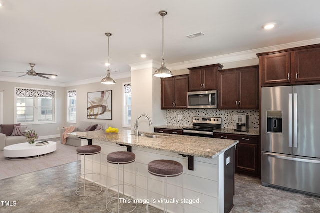 kitchen with light stone counters, hanging light fixtures, a kitchen bar, appliances with stainless steel finishes, and sink