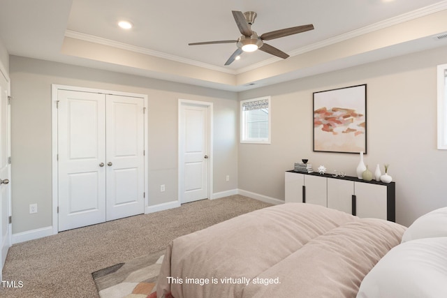 carpeted bedroom featuring a raised ceiling, ceiling fan, and ornamental molding