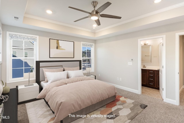 bedroom featuring ceiling fan, crown molding, ensuite bath, and a tray ceiling