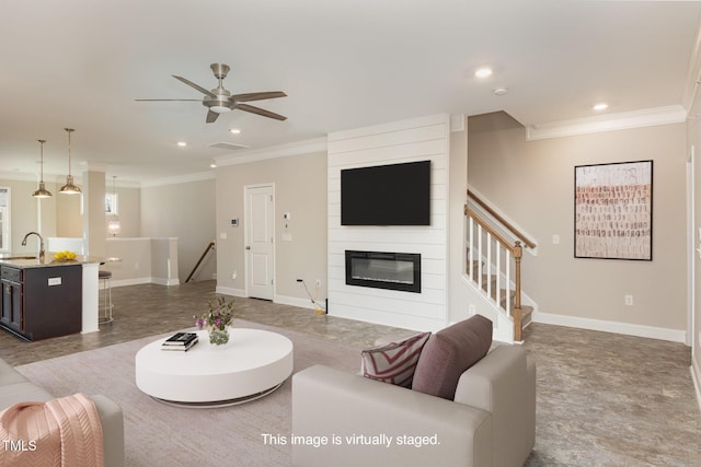 living room featuring sink, a fireplace, ceiling fan, and ornamental molding