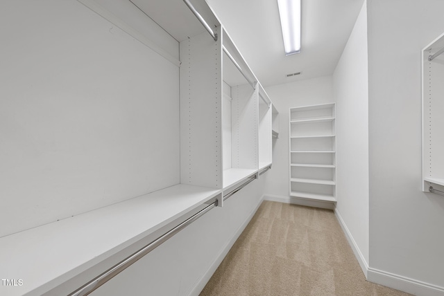 walk in closet with light colored carpet