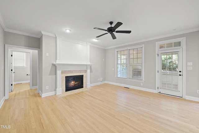 unfurnished living room with ceiling fan, light wood-type flooring, ornamental molding, and a tiled fireplace