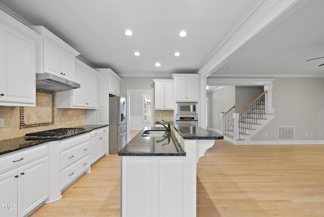 kitchen featuring sink, stainless steel appliances, an island with sink, dark stone counters, and white cabinets