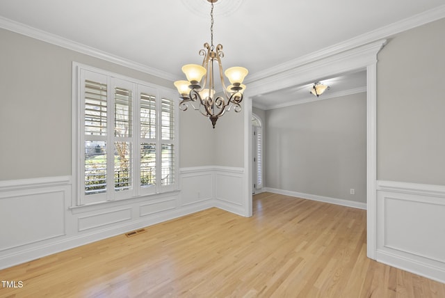 unfurnished dining area featuring crown molding, light wood-type flooring, and a notable chandelier