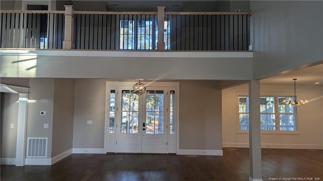 entryway with a high ceiling, dark wood-type flooring, french doors, and a notable chandelier