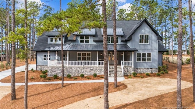 view of front of home with covered porch, driveway, a standing seam roof, and board and batten siding