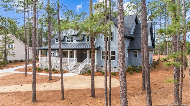 view of front of home with metal roof, a porch, a shingled roof, board and batten siding, and a standing seam roof