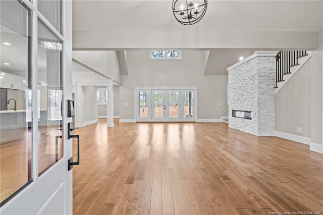 living area with a fireplace, a towering ceiling, light wood-style flooring, and an inviting chandelier