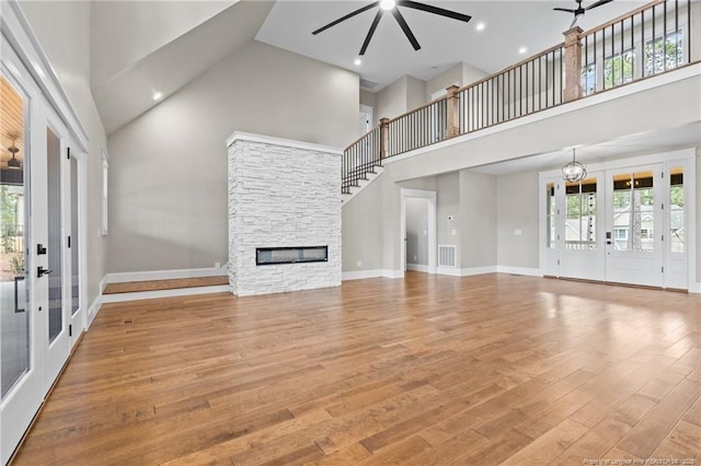 unfurnished living room with light wood-style floors, a wealth of natural light, a fireplace, and ceiling fan