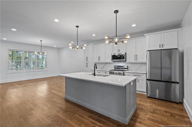 kitchen with appliances with stainless steel finishes, dark wood-type flooring, a sink, and white cabinets