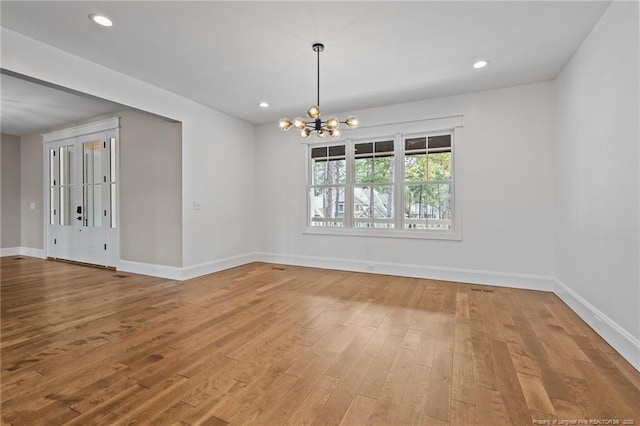 spare room with a chandelier, recessed lighting, baseboards, and wood finished floors