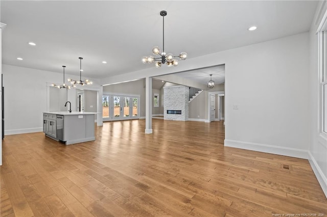 unfurnished living room with light wood-style floors, recessed lighting, a notable chandelier, and a sink