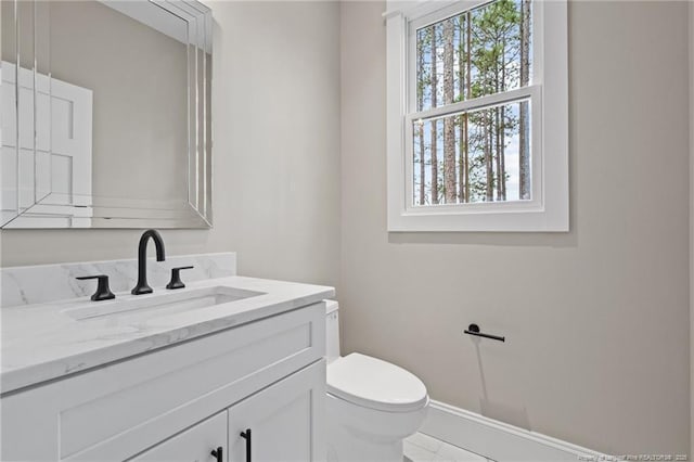 bathroom featuring vanity, toilet, and baseboards