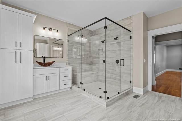 bathroom with a stall shower, visible vents, vanity, and baseboards