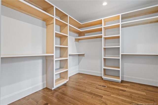 walk in closet with wood finished floors