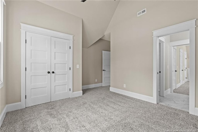 unfurnished bedroom featuring carpet, lofted ceiling, a closet, visible vents, and baseboards