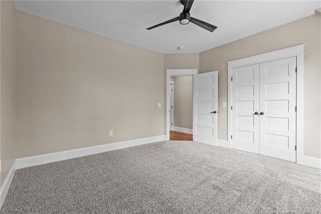 unfurnished bedroom featuring carpet floors, a closet, baseboards, and a ceiling fan