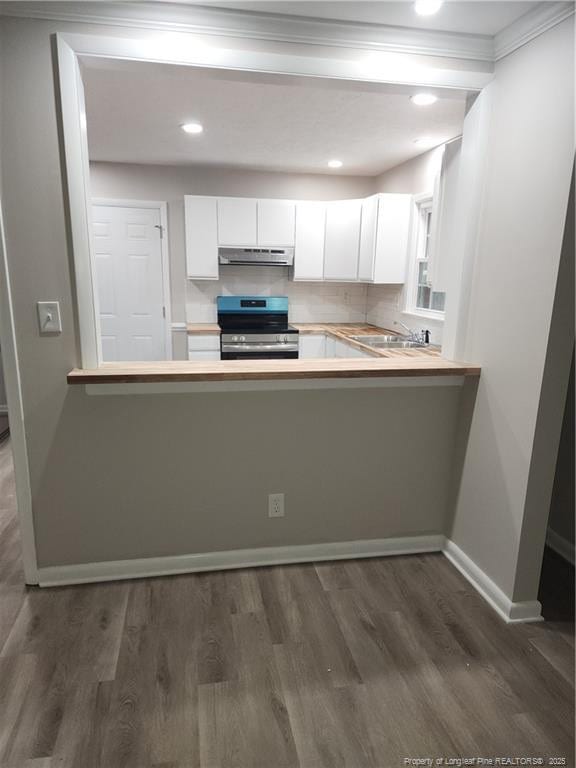 kitchen featuring kitchen peninsula, decorative backsplash, sink, stainless steel stove, and white cabinetry