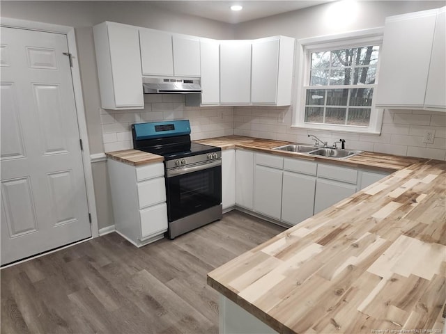 kitchen with sink, stainless steel stove, white cabinetry, butcher block counters, and extractor fan