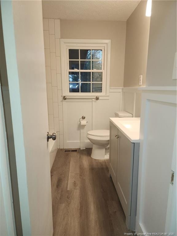 bathroom featuring vanity, toilet, wood-type flooring, and a textured ceiling