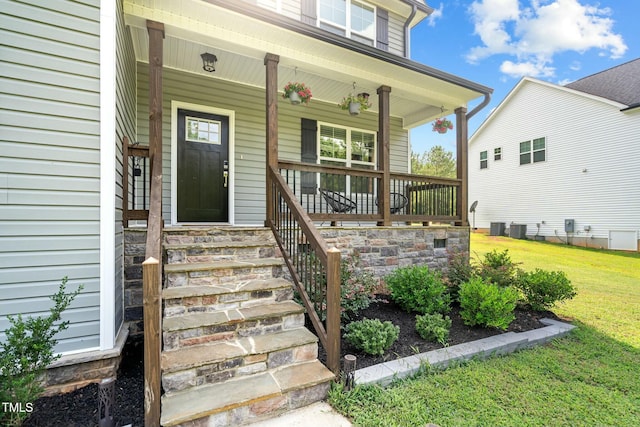 view of exterior entry with covered porch, central AC unit, and a lawn