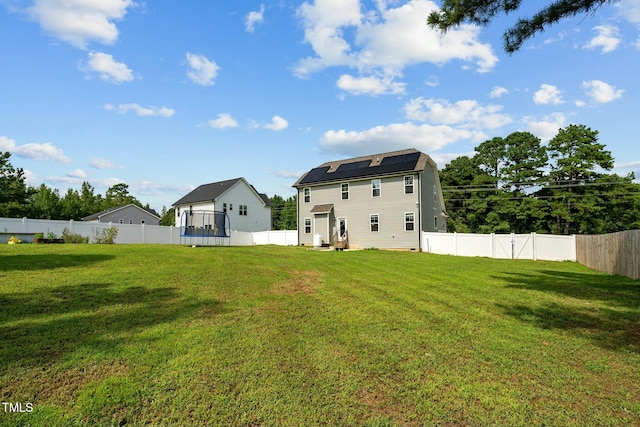 rear view of property with solar panels and a yard