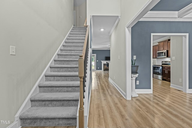 staircase with wood-type flooring and crown molding