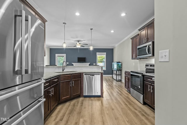 kitchen with light stone countertops, ceiling fan, sink, stainless steel appliances, and decorative light fixtures