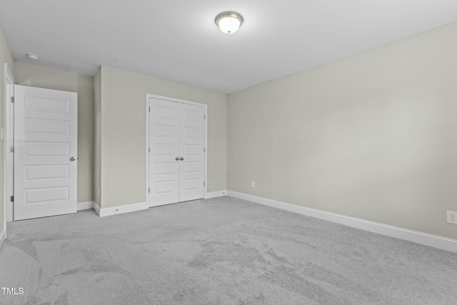 unfurnished bedroom with a closet and light colored carpet