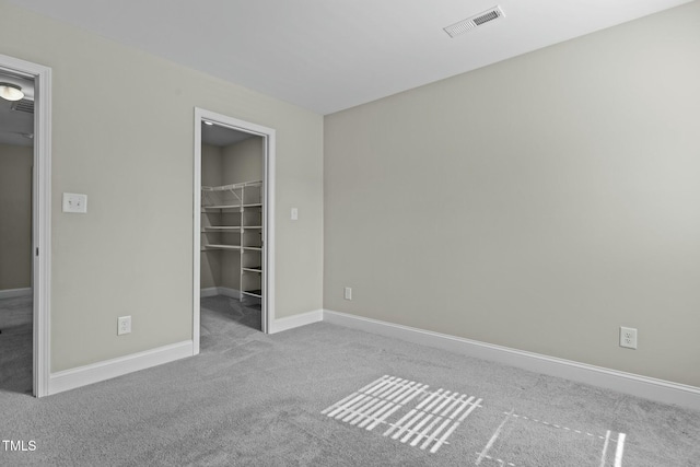 unfurnished bedroom with light carpet, a spacious closet, and a closet