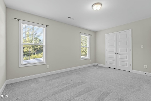 unfurnished bedroom featuring light carpet and a closet