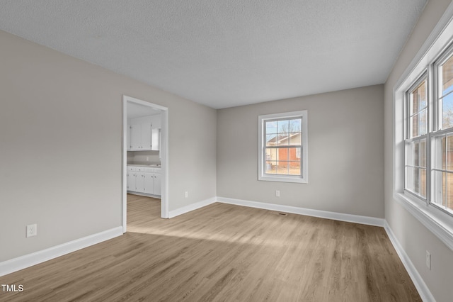 spare room featuring a textured ceiling and light wood-type flooring