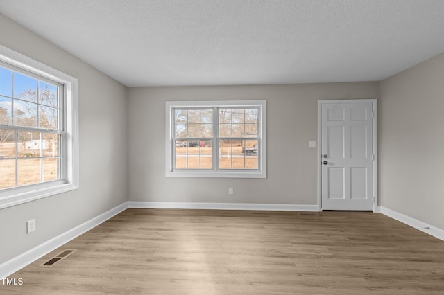 empty room featuring light wood-type flooring and a textured ceiling