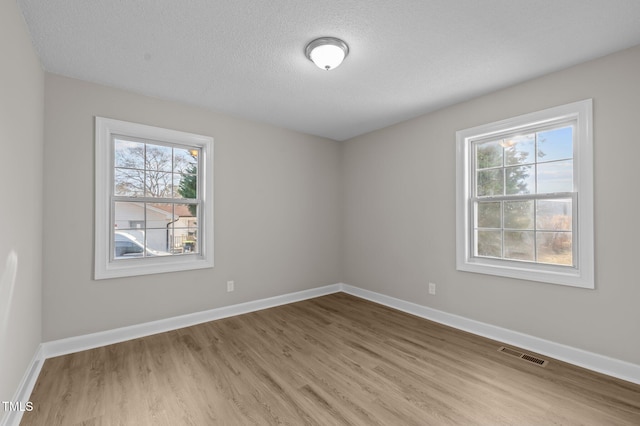 empty room with a textured ceiling and light hardwood / wood-style floors